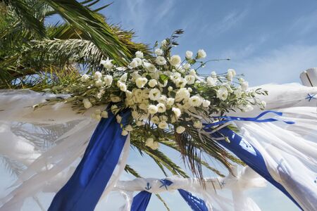 close up tropical concept wedding arch pink lotus and white orchid with blue sky and sea backgroundの写真素材