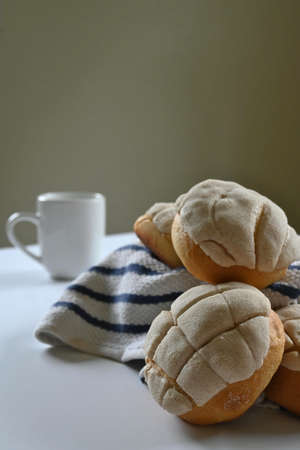 closeup of homemade Mexican vanilla bread with white and blue cotton dishcloth and white minimalist mug with handle on dark background and white surfaceの写真素材