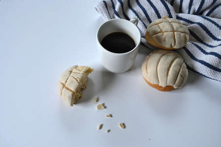 closeup of white cup of black coffee accompanied by two and a half delicious homemade Mexican shells on white cotton tea towel with blue lines and white backgroundの写真素材