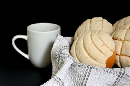closeup of traditional Mexican vanilla shells in basket with white and gray cotton dishcloth next to white coffee cup with handleの写真素材