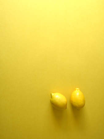 Flatlay of yellow lemons on bright yellow background, summer and spring photographyの写真素材