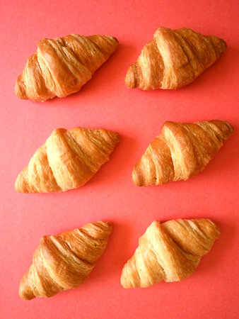 Delicious homemade golden croissants pattern flatlay on coral backgroundの写真素材