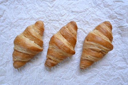 Closeup of delicious homemade golden croissants on white paper backgroundの写真素材
