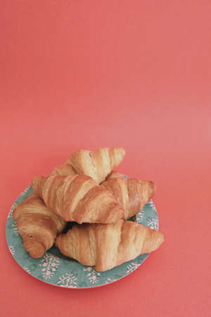 Closeup delicious homemade golden croissants on turquoise plate and salmon pink coral backgroundの写真素材