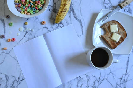 Fathers day celebration breakfast, white bowl with colorful cereals and milk, white cup with black coffee and square white plate with toast and butter, ripe banana, blank greeting card, marble background, copy spaceの写真素材