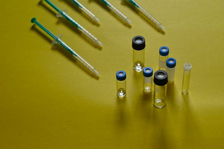 different vaccines concept, syringes pointing to different vials of different sizes, on yellow background with copy spaceの写真素材
