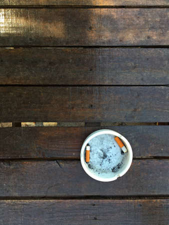 Overhead shot of wooden table with ashtray with tobacco butts, copy spaceの写真素材