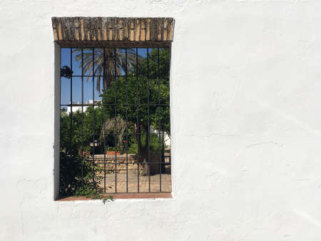 Horizontal closeup of white Spanish Andalusian facade with large window and patio inside, with copy spaceの写真素材