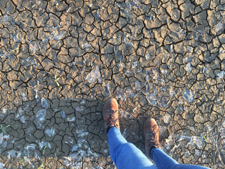 Soil overhead with desertification, drought, woman legs in jeans and field boots, copy spaceの写真素材