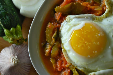 Close-up of plate of Manchego pisto with egg, surrounded by ingredientsの写真素材