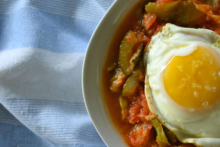 Horizontal overhead shot of Manchego pisto dish with egg, blue striped cloth background, with copy spaceの写真素材