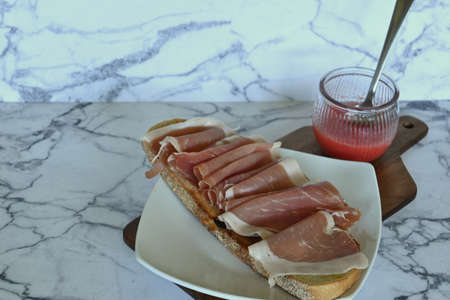 Horizontal closeup of cured ham with tomato toast, marble background with copy spaceの写真素材