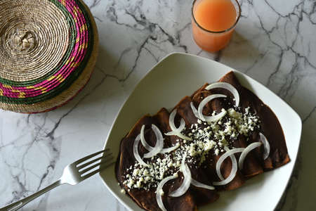 Overhead shot of enfrijoladas on marble table next to tortillera and grapefruit juice, with copy spaceの写真素材