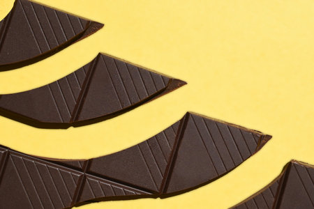 Chocolate bar broken in pieces, on yellow