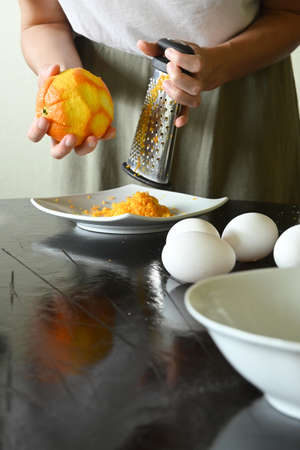 Portrait of young woman holding grated orangeの写真素材