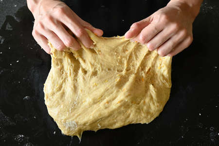 Young woman's hands stretching doughの写真素材