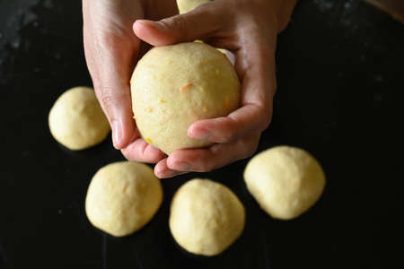 Woman's hands holding ball of doughの写真素材