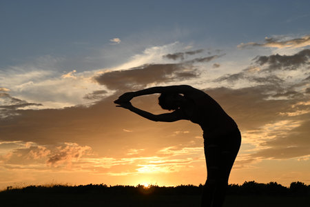 Front shot of slim young woman doing yoga palm pose in golden hourの写真素材