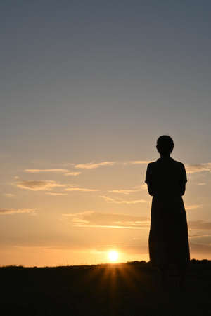 Close-up of a woman in a dress contemplating a sunsetの写真素材