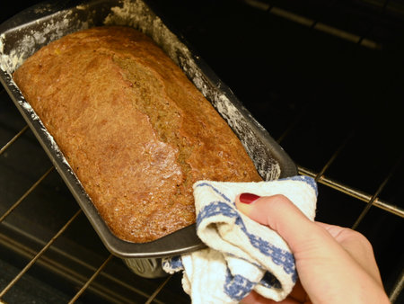 Freshly baked cake being taken out of the oven by a woman's hand