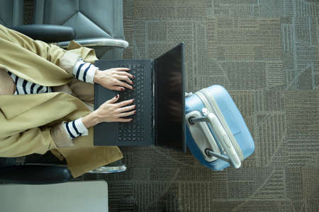 Top view of unrecognizable woman working with laptop in airport next to luggage with copy spaceの写真素材