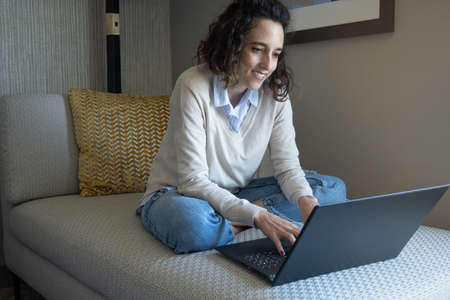 Close-up of latin woman sitting on sofa while working with computer, home office concept, with copy spaceの写真素材