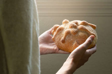 Front close-up of person holding pan de muerto, selective focus and copy spaceの写真素材