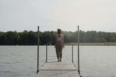 Unrecognizable woman on her back on a dock in front of lake, freedom concept, with copy space.の写真素材