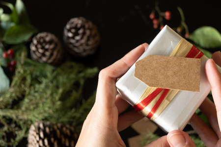 Close-up of hands holding gift with empty card, with copy spaceの写真素材
