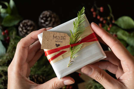 Close-up horizontal of gift with "made with love" label held by hands, selective focusの写真素材