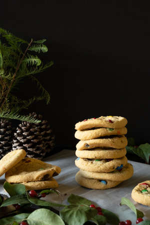 Vertical front shot of cookies stacked with Christmas decorations, black background and copy space.の写真素材