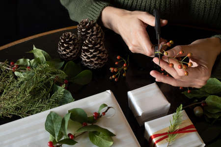 Woman cutting plant pieces to decorate Christmas gifts, with copy space.の写真素材
