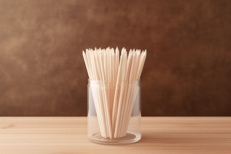 Close-up of toothpicks in a transparent jar with a rustic brown backgroundの素材