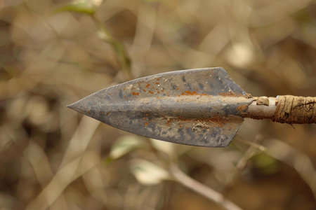 Rusty metal arrowhead attached to a wooden shaft is showing its ageの素材