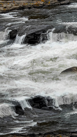 Reflective Waterfall Stream with Mirrored Flow Over Dark Rocksの写真素材