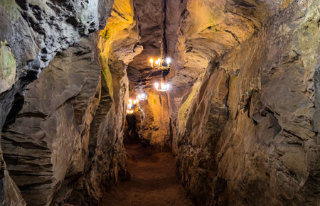 Illuminated Cave Passage with Chandeliers and Metal Rail Pathwayの写真素材