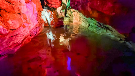 Colorful Illuminated Cave with Reflections on Underground Waterの写真素材
