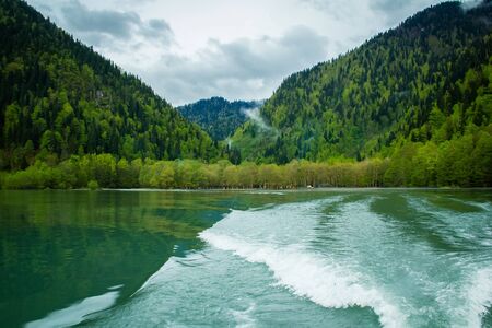 green mountain lake surrounded by spring mountainsの写真素材