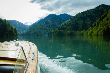 retro boat sailing on Ritsa lake among the mountainsの写真素材