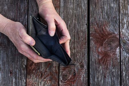 an elderly person has a financial crisis, holds an empty wallet in his handの写真素材