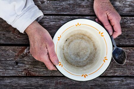 old mans hands hold an empty old bowlの写真素材