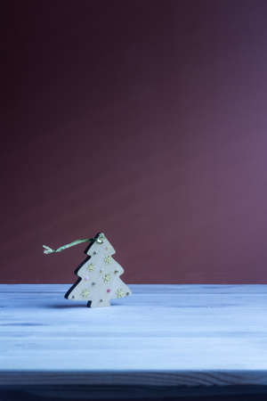 Christmas toy in the form of a wooden Christmas tree, standing on a blue table on a purple backgroundの写真素材