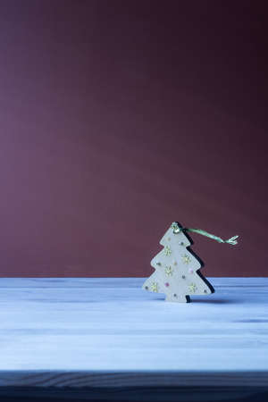 Christmas toy in the form of a wooden Christmas tree, standing on a blue table on a purple background.の写真素材