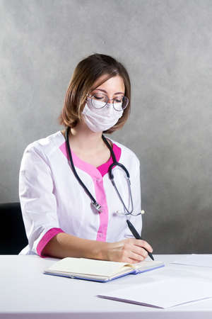 a young female doctor writes a prescription for a patient.の写真素材