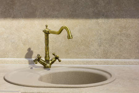 round porcelain tile kitchen sink on the kitchen countertop and retro brass faucetの写真素材