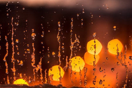abstract background, streams of rain and snow on the glass on the background of street lighting