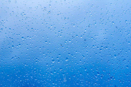 abstract background, raindrops on the glass against the blue stormy sky