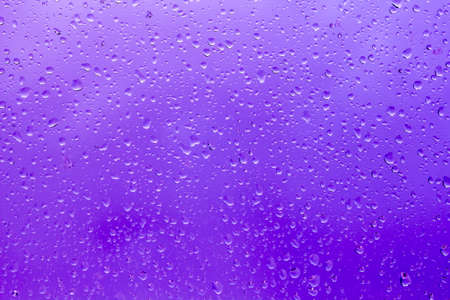 abstract background, raindrops on the glass against the blue stormy skyの写真素材