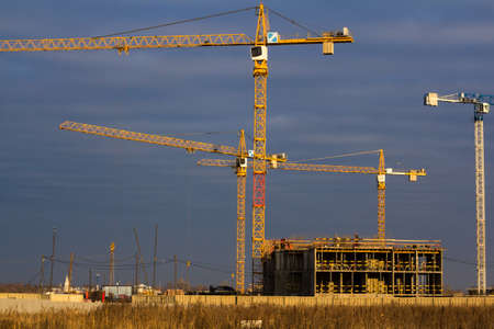 construction site with tower cranes in a field against a dark blue skyの写真素材