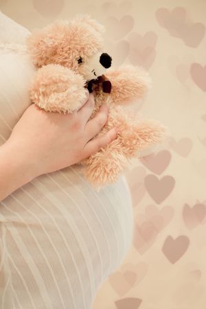 Pregnancy woman holding a teddy bear over her bellyの写真素材